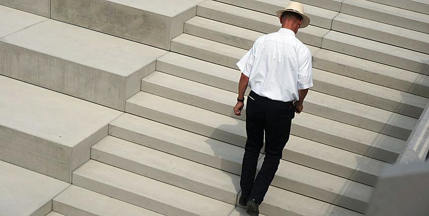 Bild zeigt einen Mann mit Hut der eineTreppe am Ufer der Henne in Meschede hoch geht. Foto: LWL / Darius Djahanschah (vergrößerte Bildansicht wird geöffnet)